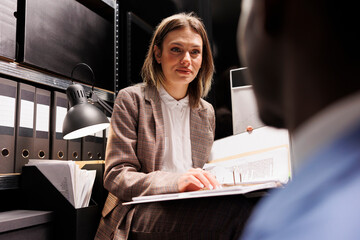 Managers organizing at business files, analyzing bureaucracy record in storage room. Diverse...