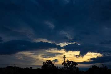 Sunset in the city, dramatic sky with clouds and silhouette of trees