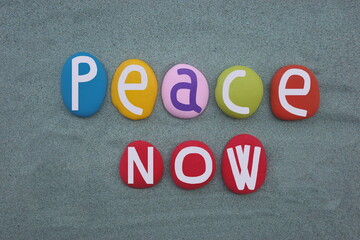 Peace now, creative slogan composed with hand painted multi colored stone letters over green sand