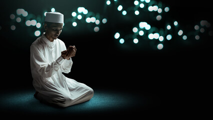 Muslim man sitting and raised her hands and prayed to Allah