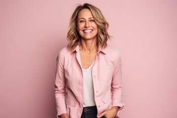 Portrait of a smiling mature businesswoman standing against pink background.