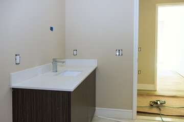 At bathroom, installation of wash basins, cabinet with drawers, white porcelain sink with stainless steel faucet