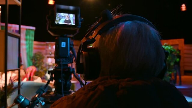 Cameraman filming a television talk show on a professional camera. Video production backstage in a dark studio