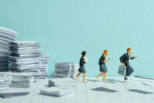 Miniature People Toy Figure Photography. Homework Concept. The Group Of Pupil Students Running On Paperwork Task Document Pile Stack