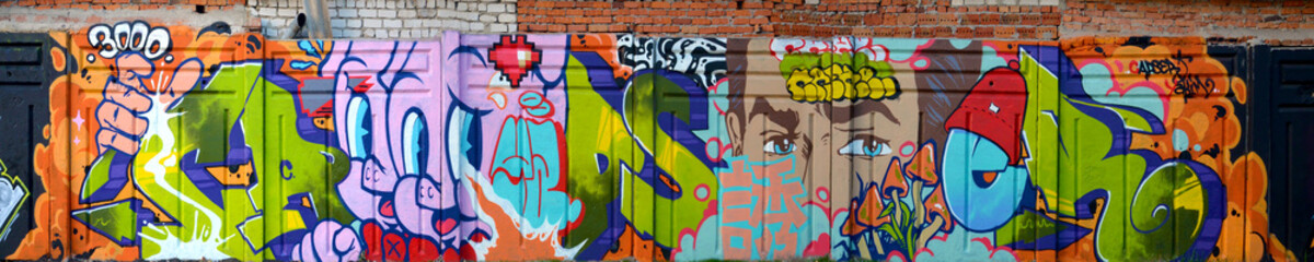 Fototapeta premium The old wall decorated with paint stains in the style of street art culture. Colorful background of full graffiti painting artwork with bright aerosol outlines on wall. Colored background texture