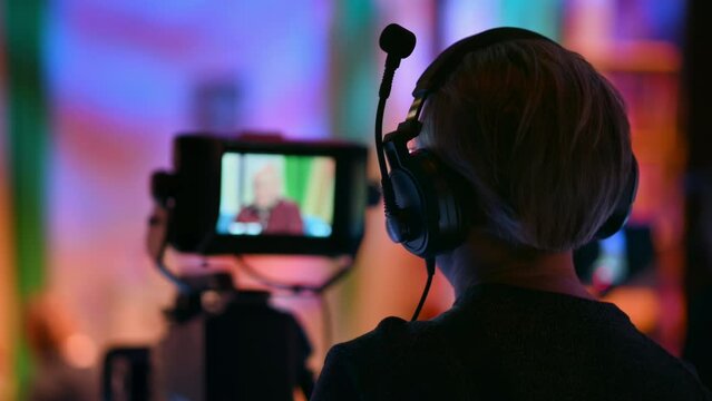 Cameraman filming a television talk show on a professional camera. Video production backstage in a dark studio