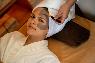 Serene ambiance of spa salon, woman customer indulges in rejuvenating with charcoal face cream...