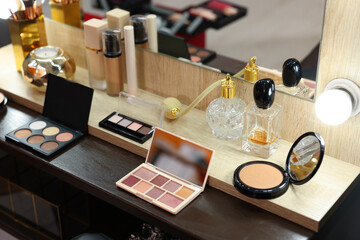 Makeup room. Cosmetic products and perfumes on wooden dressing table indoors
