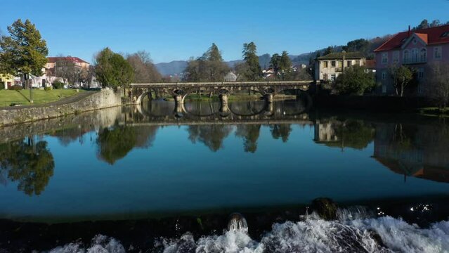 Old bridge crossing River Vez in town of Arcos de Valdevez in Portugal reflects perfectly in calm water