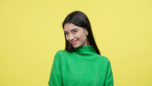 Shy, bashful Caucasian young woman portrait, hiding eyes over yellow background. Flirting and charming lady with smile cute embarrassment.
