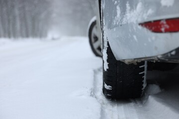 Car with winter tires on snowy road outdoors, closeup. Space for text