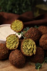 Delicious falafel balls and sauce on wooden board