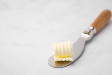 Fototapeta na wymiar Tasty butter curl and knife on white table, closeup. Space for text