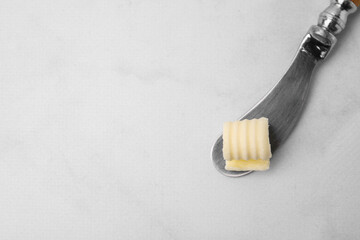 Fototapeta na wymiar Tasty butter curl and knife on white table, top view. Space for text