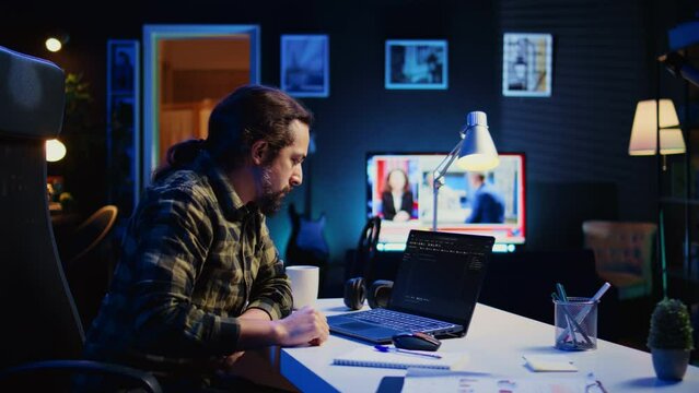 Skilled computer scientist writes code on laptop screen while in living room office using programming languages. Self employed IT specialist working on fixing database errors from home, camera B
