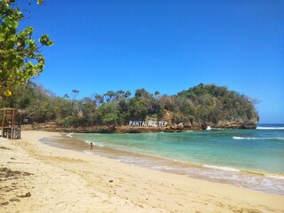 beautiful white sand beach with blue water, with thick cloudy skies