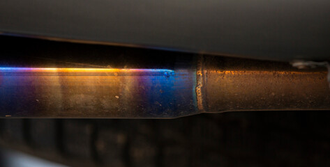 Close-up of a car exhaust pipe with a blue light.