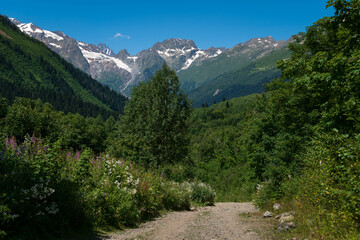 Fototapeta na wymiar View of the Dombay-Ulgen gorge in the mountains of the North Caucasus and the trail to the Chuchkhur waterfall near the village of Dombay on a sunny summer day, Karachay-Cherkessia, Russia