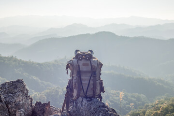Binocular with backpack on top of rock mountain at sunset - obrazy, fototapety, plakaty
