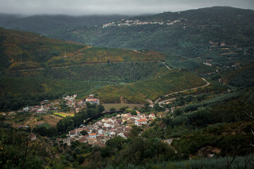 Obraz premium A town on a misty morning at the foot of the Serra da Estrella mountains in Portugal.