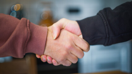 Close up business people shaking hands successful partnership deal welcoming opportunity. Greeting each other with a firm handshake indoors