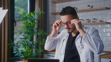 Experienced doctor with glasses wearing white coat taking patient reports from his assistant and examines. Male practitioner doing paperwork