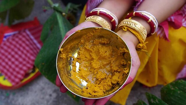 Slow motion shot of a Hindu bride holding yellow turmeric on her hands.
