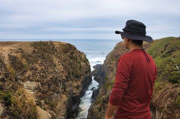 Fototapeta na wymiar Turista mirando la naturaleza en el borde costero