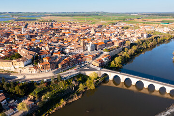 Scenic drone view of small ancient Spanish town of Tordesillas on banks of Duero river in province of Valladolid on sunny spring day..