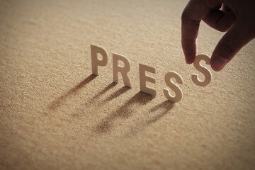 PRESS wood word on compressed or corkboard with human's finger at S letter..