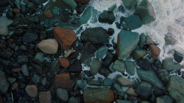 Aerial: Waves crashing over boulders in slow motion. Oamaru, Otago, New Zealand.