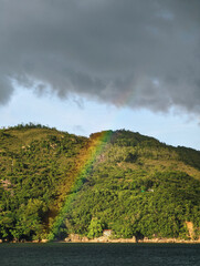 Fototapeta premium A beautiful natural scene where a vibrant rainbow is visible against a mountain.