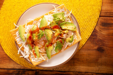 Fried wheat flour toast with pickled pork skin, sour cream and vegetables with hot sauce, in Mexico is called Chicharron preparado, traditional street food, pickled pork skin are known as Cueritos.