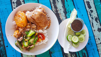 Rice with massaman chicken and stir-fried zucchini, Thai food, with chili paste and shrimp paste on the side and fresh vegetables such as cucumbers and cabbage.