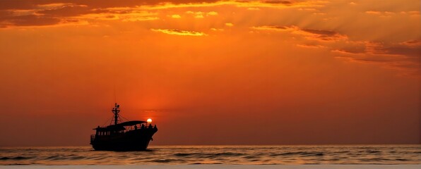 Silhouette of a fishing boat at sunset in the sea.