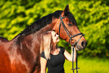 Horse and girl head portraits against a green background in the sunshine