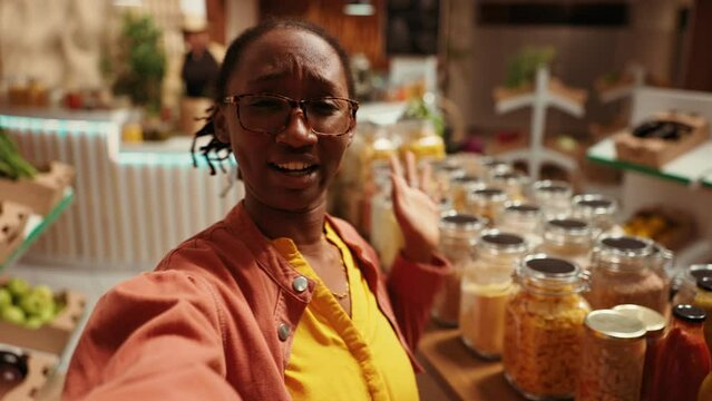 POV Of African American Client Promoting Local Bio Supermarket On Social Media Networks, Filming Video Online To Create Ad. Woman Presenting Additives Free Bulk Items And Produce. Handheld Shot.