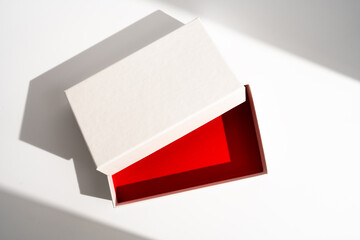 White square gift box mockup on white background, harsh shadows, red inside. From above, top view, minimalist concept, mock up, luxury