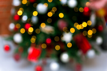 Blurred Lights on Decorated Christmas Tree. A close-up of a Christmas tree blurred in the background with a bokeh effect from the festive lights, evoking a warm, celebratory atmosphere.