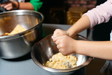 Child Helping in Kitchen Crushing Cookies. A child's hands actively crushing cookies in a metal bowl, participating in a kitchen baking activity.