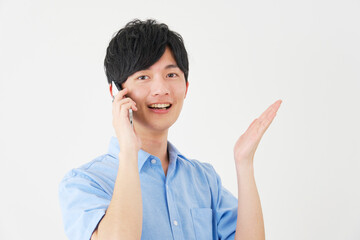 手の平で右を指しながらスマートフォンで電話する男性　白背景