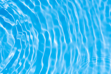 Water surface. Bluewater waves on the surface ripples blurred. Defocus blurred transparent blue colored clear calm water surface texture with splash and bubbles. Water waves with shining pattern.