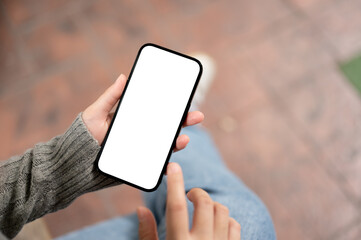 A close-up image of a woman using her smartphone while sitting outdoors. a smartphone mockup.