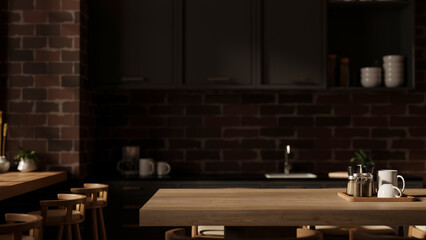 A space on a hardwood dining table in a modern, dark kitchen with black counters and a brick wall.