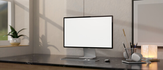 Close-up image of a white-screen computer mockup on a black marble table in a modern home office.