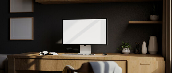 A modern home office with a white-screen computer mockup on a wooden desk against the black wall.