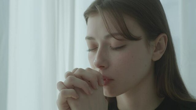 A young woman praying, close up
Blue, cool tone