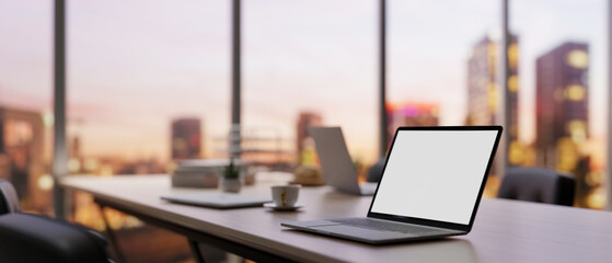 Close-up image of a laptop computer on a meeting table in a modern company meeting room.