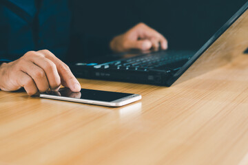 Male hand using notebook and hand pointing at mobile phone screen, working on office table Close-up...