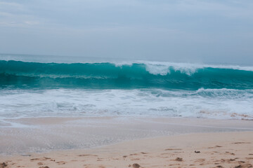 A large turquoise wave near the shore. Wave for surfers in the form of a tube